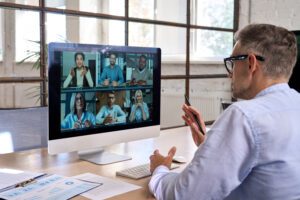 Corporate leader manager leading videoconference with diverse team business people having digital group video call conference working in office at online virtual meeting on pc computer. Over shoulder