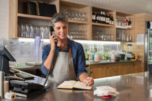 Female business owner making a cloud phone call using a desk phone.