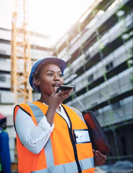 Field service worker using a mobile phone on a job site to stay connected while working on location