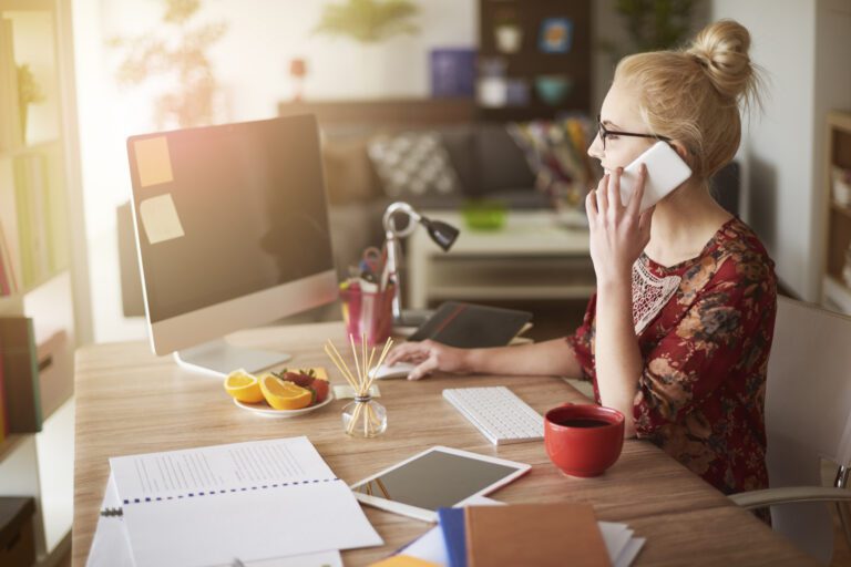 Business woman working from home and talking on a mobile device.