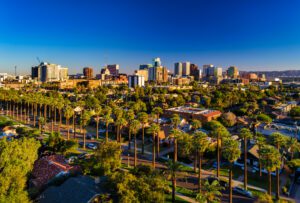 Aerial of Downtown Phoenix skyline with a residential neighborhood with many palm trees in the foreground.